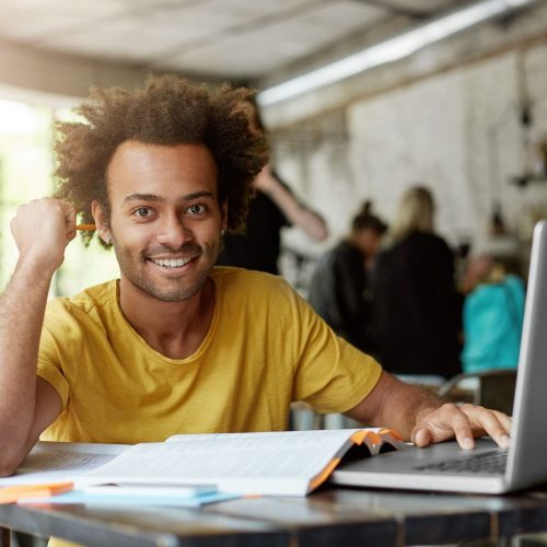 happy-positive-african-american-college-student-with-cheerful-cute-smile-using-wireless-internet-connection-laptop-computer-coffee-shop-while-looking-information-online-research-project-2